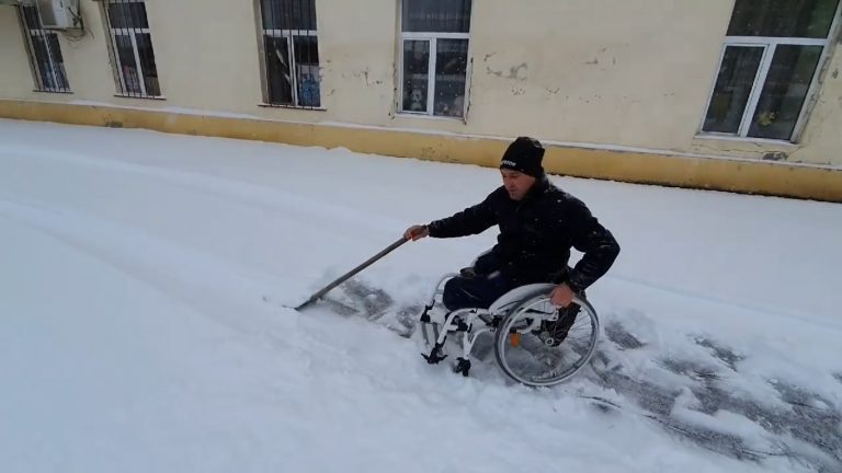 Exemplu de urmat. Un bărbat în scaun cu rotile deszăpezește trotuarul din fața casei VIDEO